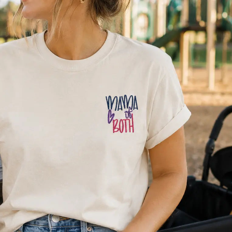 Woman wearing a white t-shirt with text, sitting outdoors near playground equipment.
